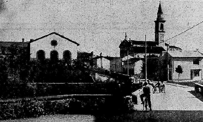 Via Delma, con la filanda a sinistra e la chiesa sullo sfondo, in una foto del 1957.